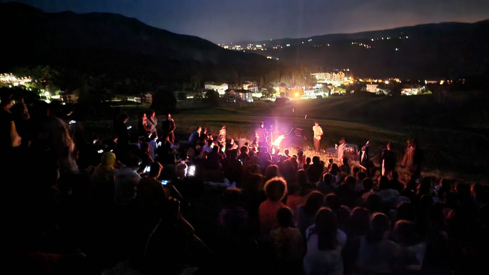 Falò serale al camp con i ragazzi riuniti attorno al fuoco