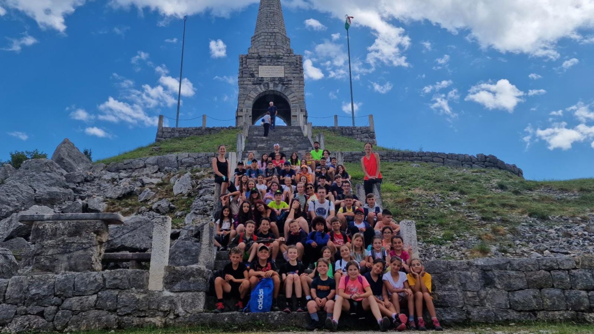 Ragazzi del camp si arrampicano su una parete di roccia con le montagne sullo sfondo