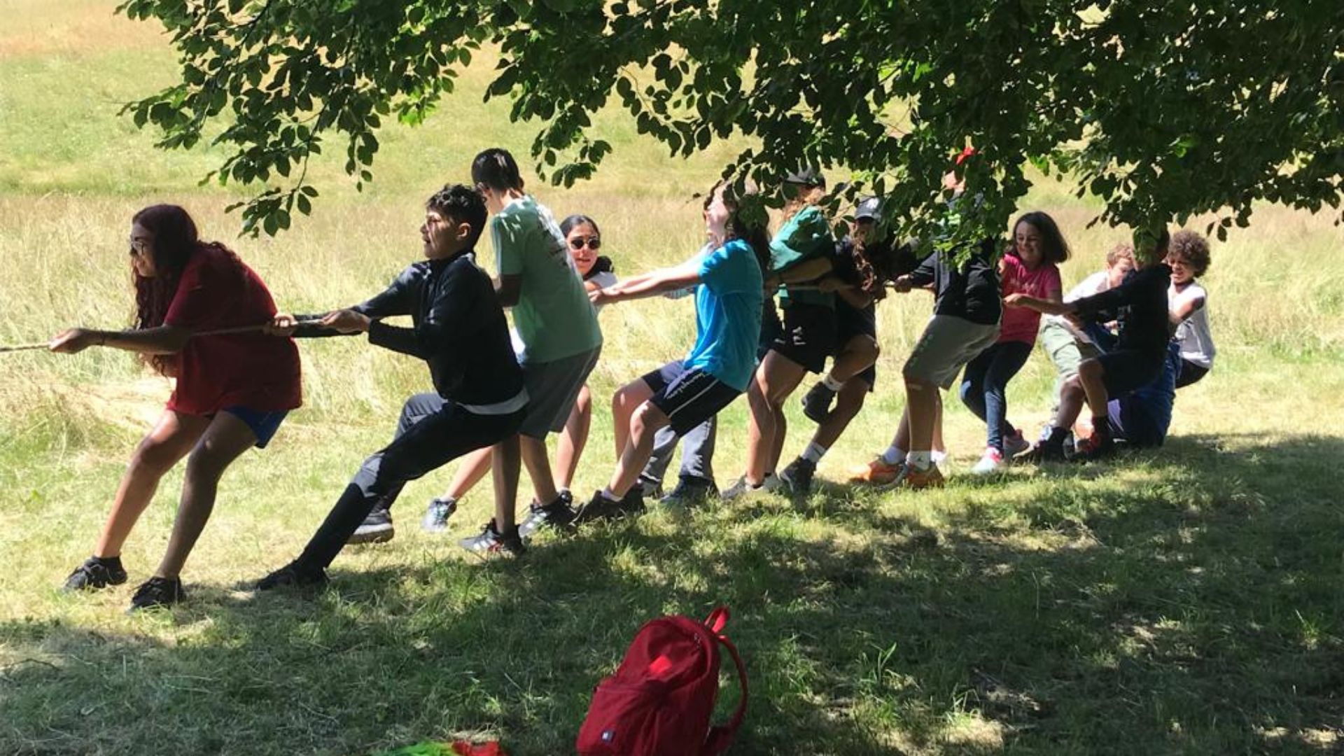 Bambini del camp giocano al tiro alla fune in un prato di montagna