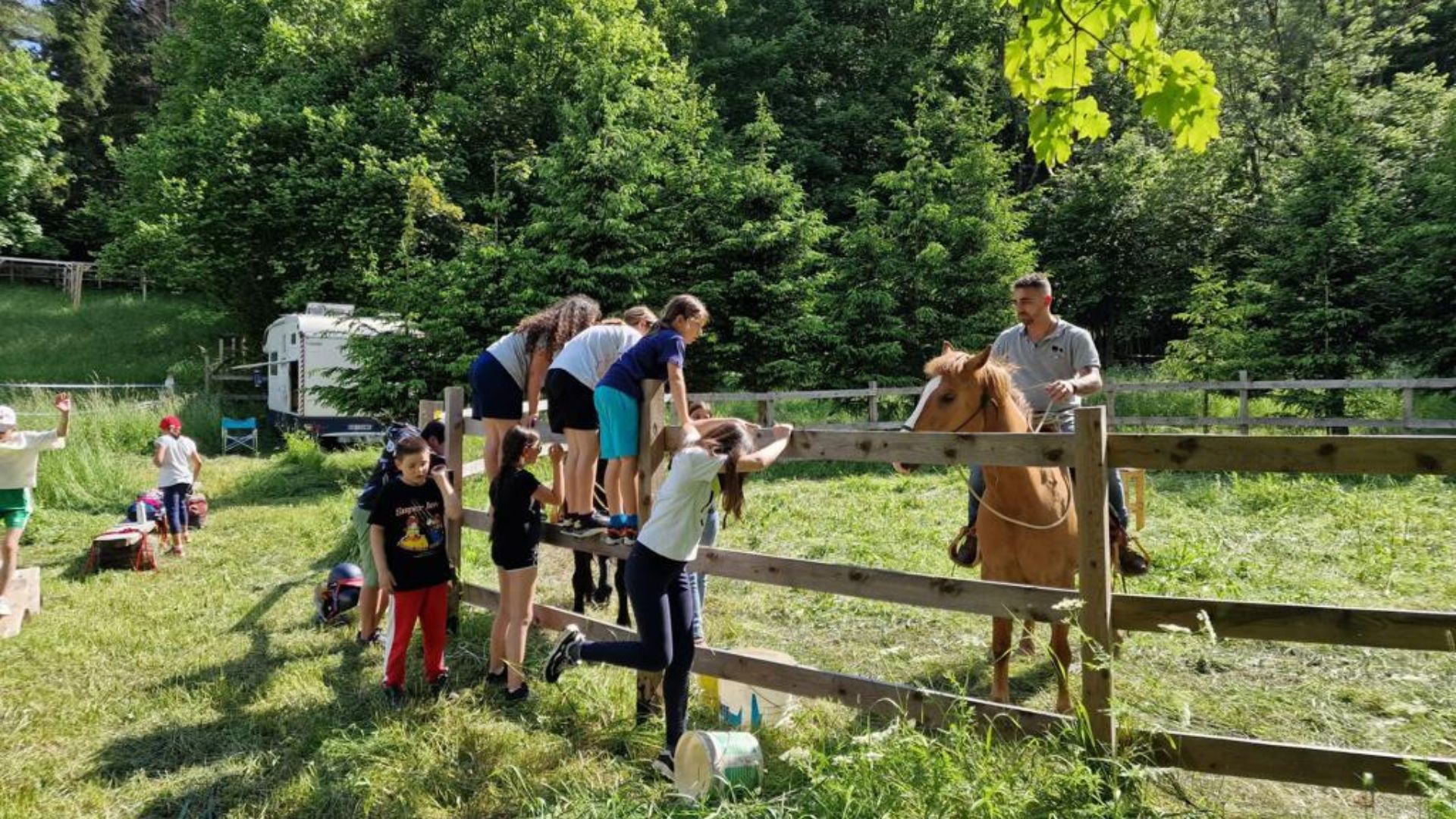 Gruppo di bambini del camp seduti nel prato durante un'attività
