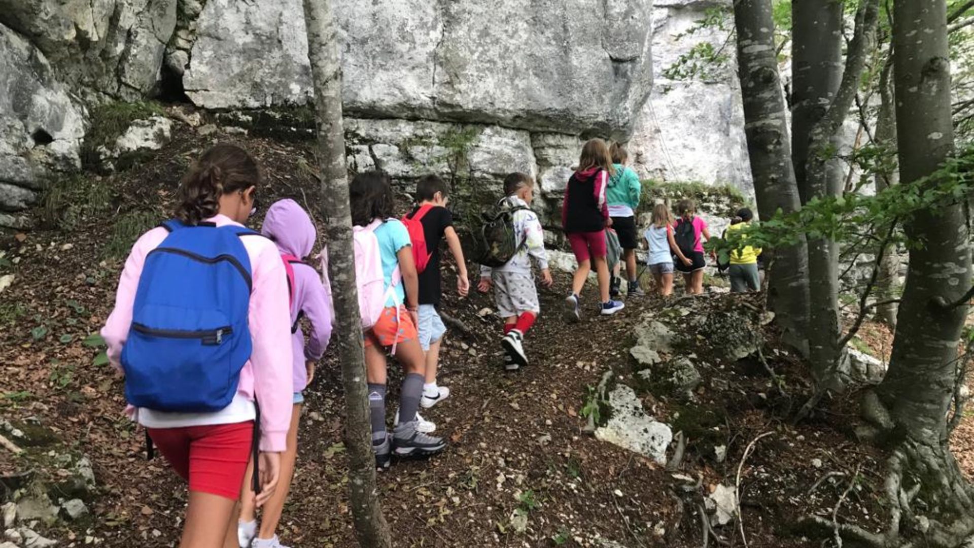 Bambini del camp camminano lungo un sentiero con gli zaini in spalla
