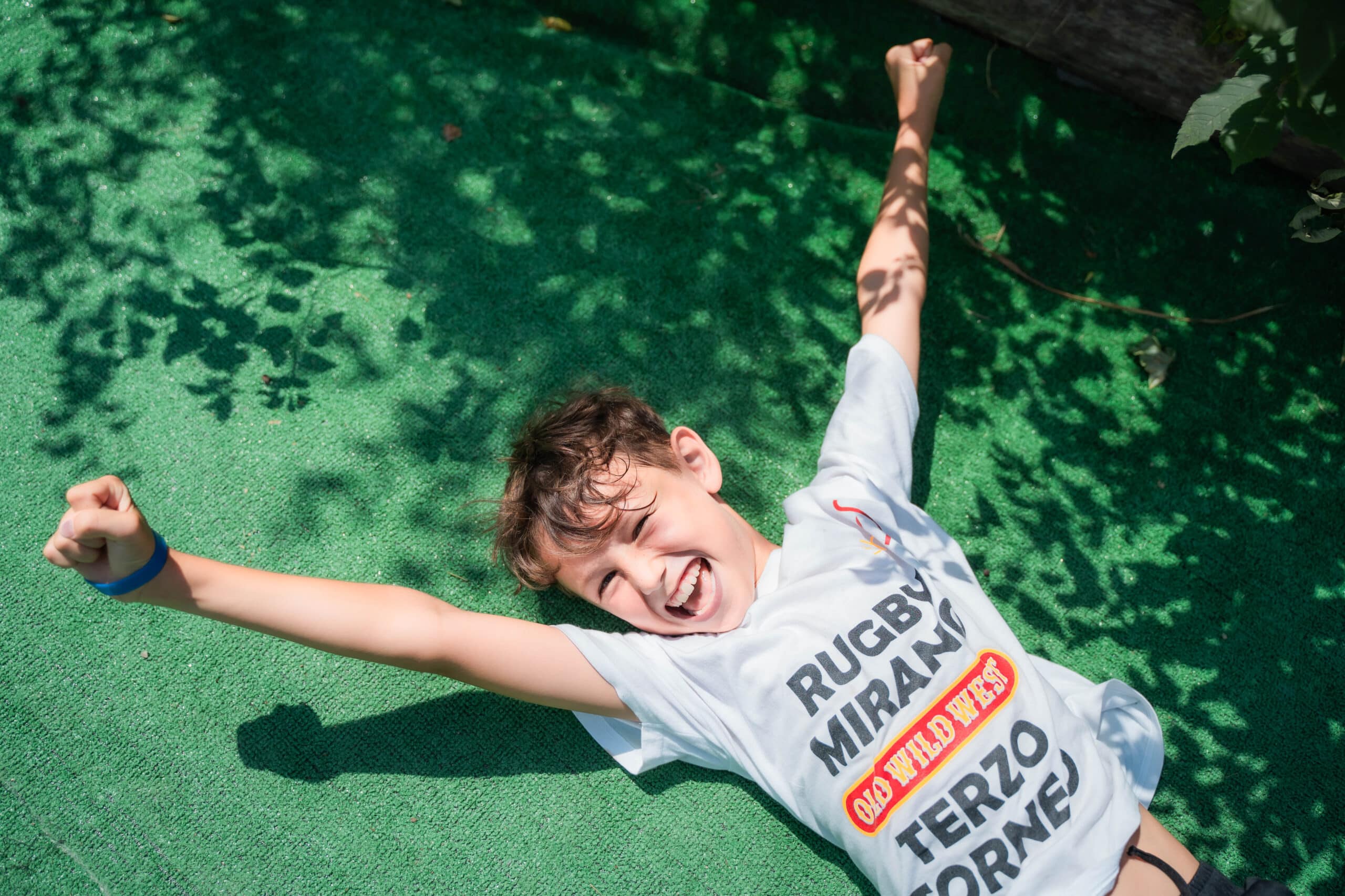 Un bambino del camp ride a braccia aperte disteso sull'erba